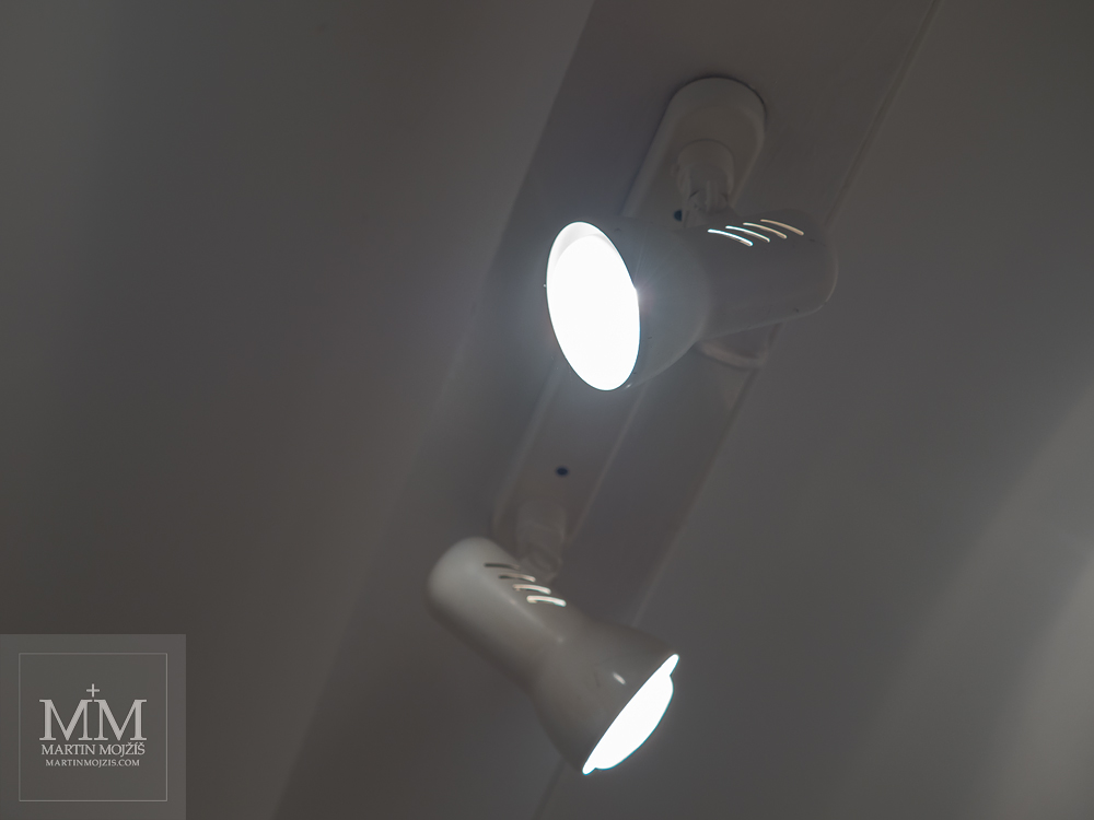 Dva svítící bodové reflektory na stropě. Fotografie vytvořená objektivem Olympus M. Zuiko digital ED 40 - 150 mm 1:2.8 PRO.